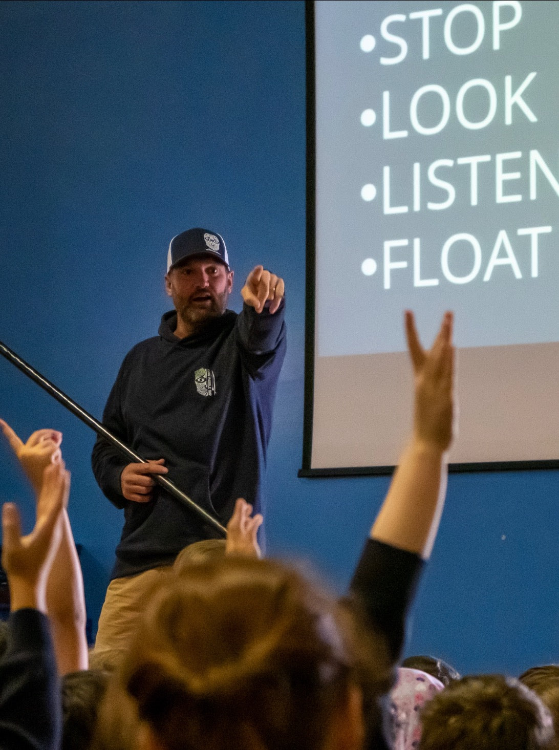 Brendon Prince engaging pupils in a water-safety talk with the Blue Cross Code on screen